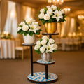 Three-tier mosaic multi-level plant stand with colorful ceramic shelves and black metal frame for indoor or outdoor use.