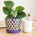 Colorful mosaic flower pot in purple and green with floral design, perfect for indoor or outdoor gardening.