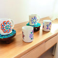 Handpainted coffee mugs with colorful floral designs, showcasing unique artistic patterns on ceramic surfaces.