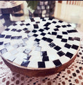 Handmade black and white checkered mosaic plant stand with a sturdy base and decorative pattern, perfect for indoor or outdoor plants.