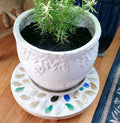 Handcrafted earth tone mosaic plant stand with intricate tile design, suitable for displaying potted plants indoors or outdoors.