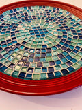 Deep crimson ceramic plate featuring an ocean breeze mosaic design, showcasing vibrant blue and green patterns.