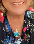 Ocean blue shell medallion necklace featuring a large shell pendant on a delicate chain, worn as stylish jewelry accessory.