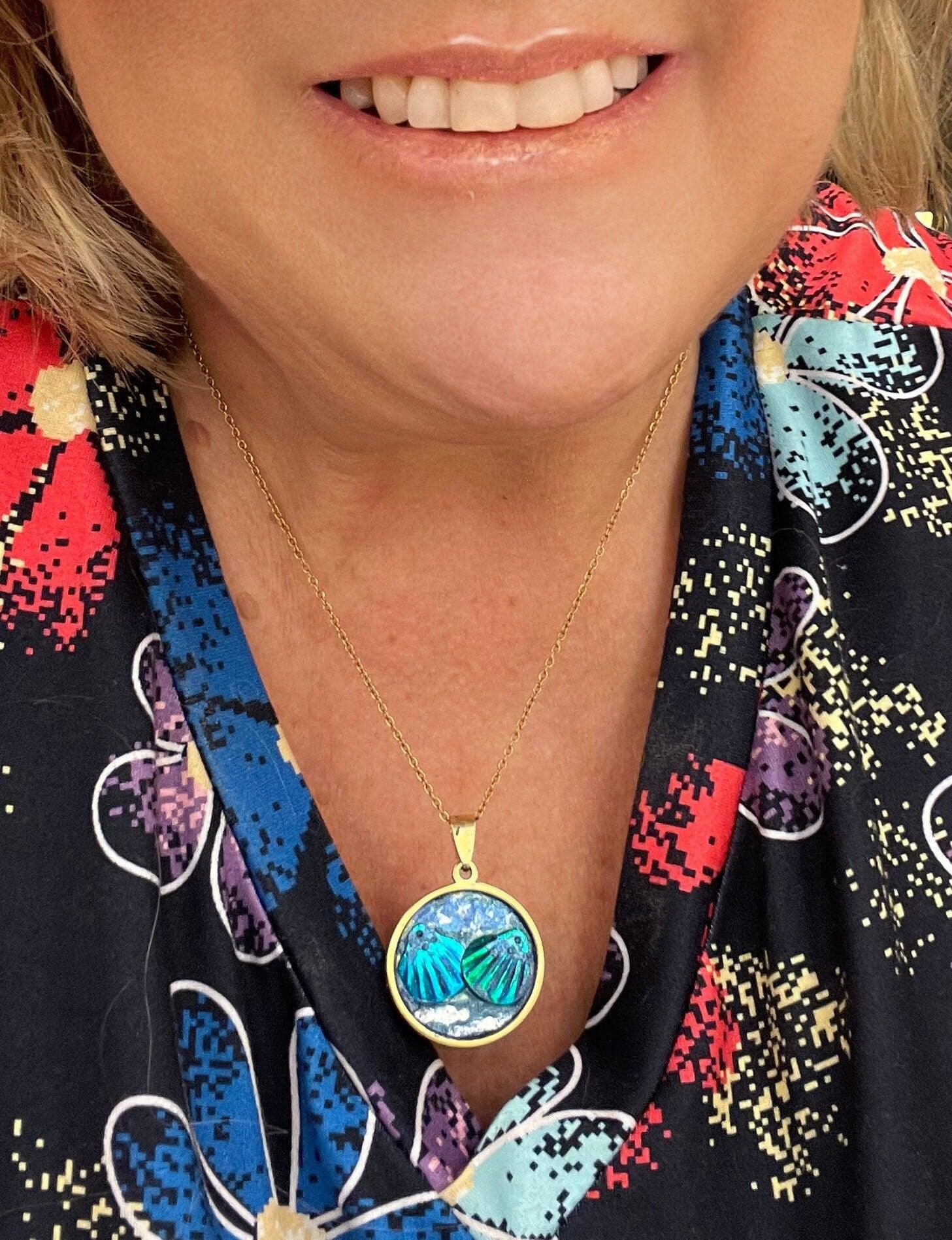 Ocean blue shell medallion necklace featuring a large shell pendant on a delicate chain, worn as stylish jewelry accessory.
