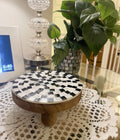 Handmade black and white checkered mosaic plant stand with a sturdy base and decorative design.