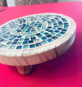 Handcrafted round turquoise glass mosaic plant riser with intricate mosaic pattern for decorative plant display.