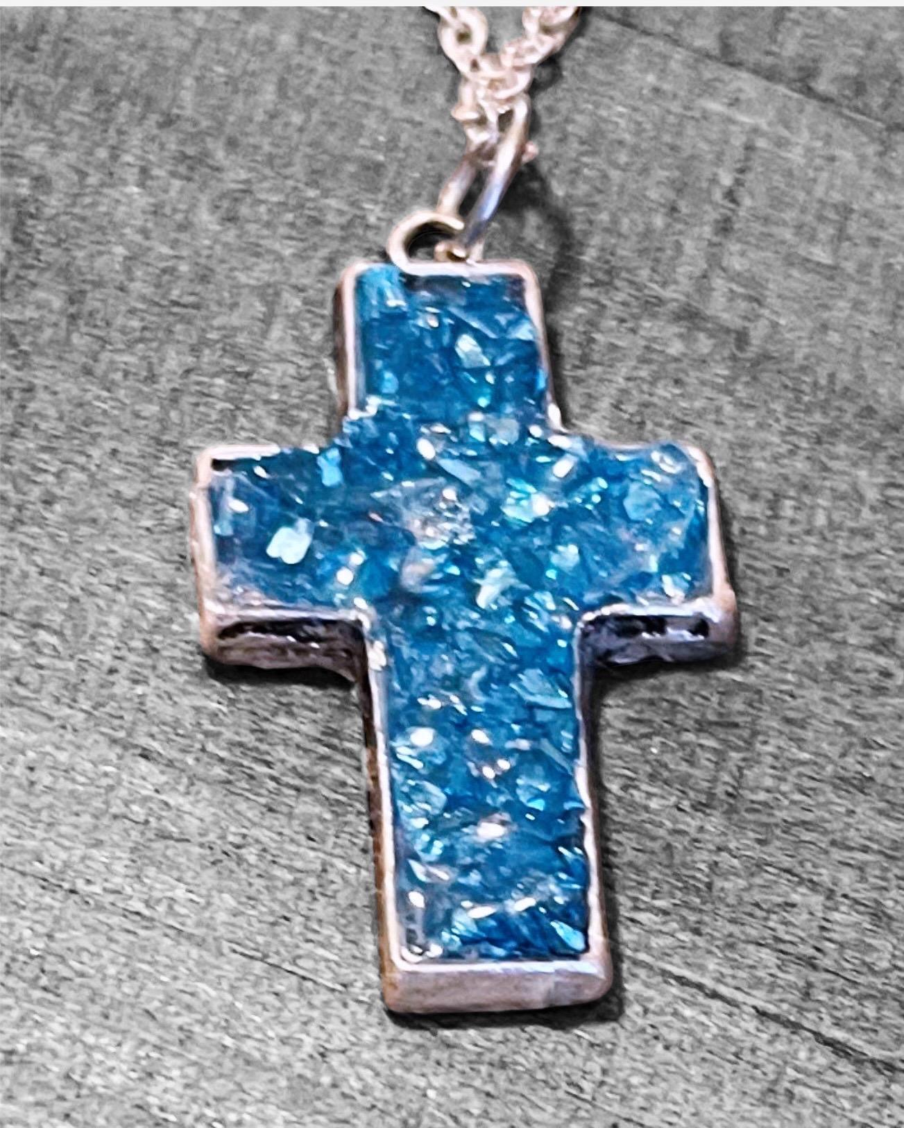 Turquoise glass cross pendants set in silver, featuring detailed craftsmanship and a polished finish on a neutral background.