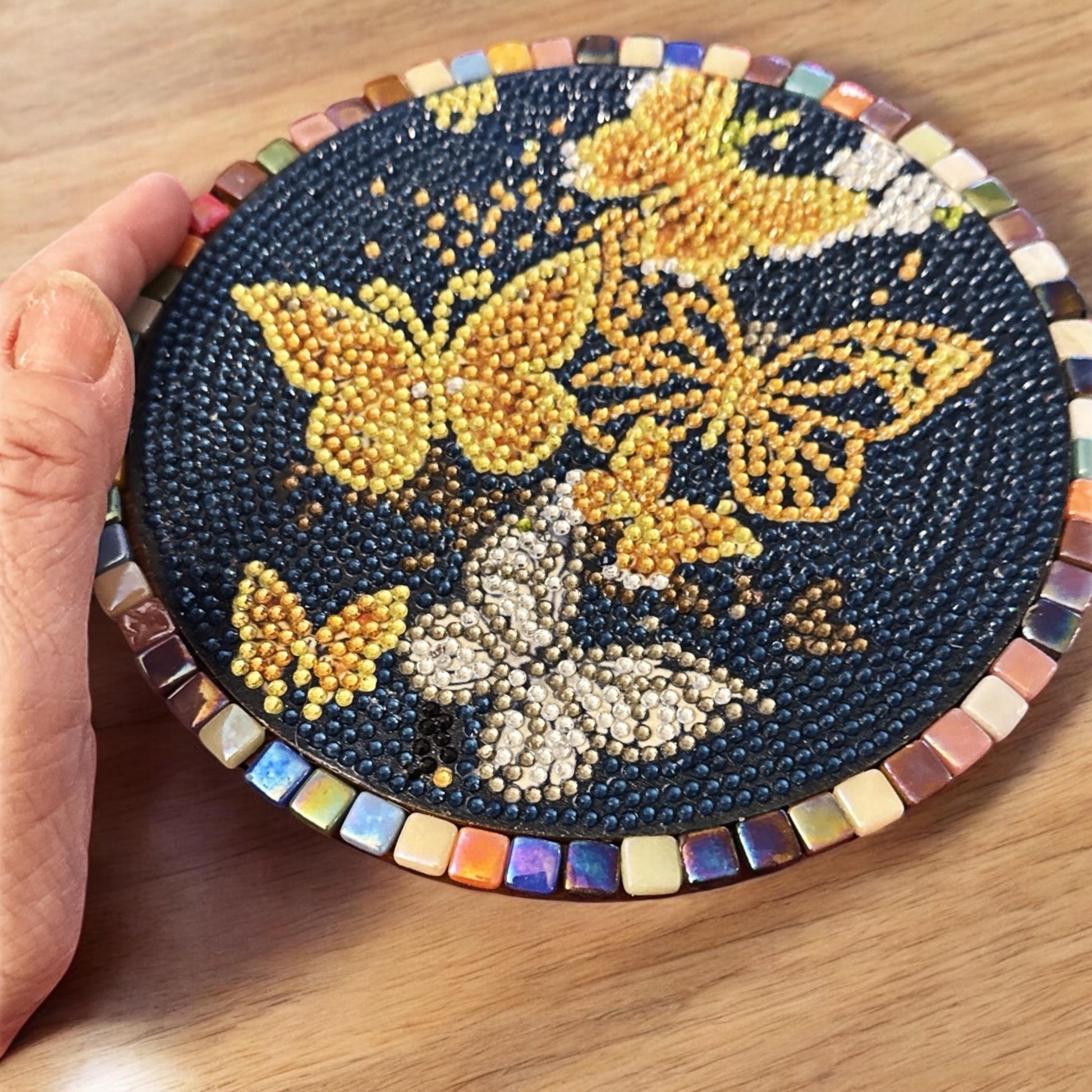 Butterfly crystal mosaic trivet with decorative display featuring colorful glass and intricate butterfly design on a wooden surface.