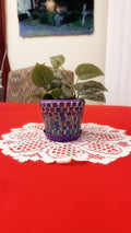 Purple and green mosaic flower pot with floral design, showcasing vibrant colors and intricate tile pattern.