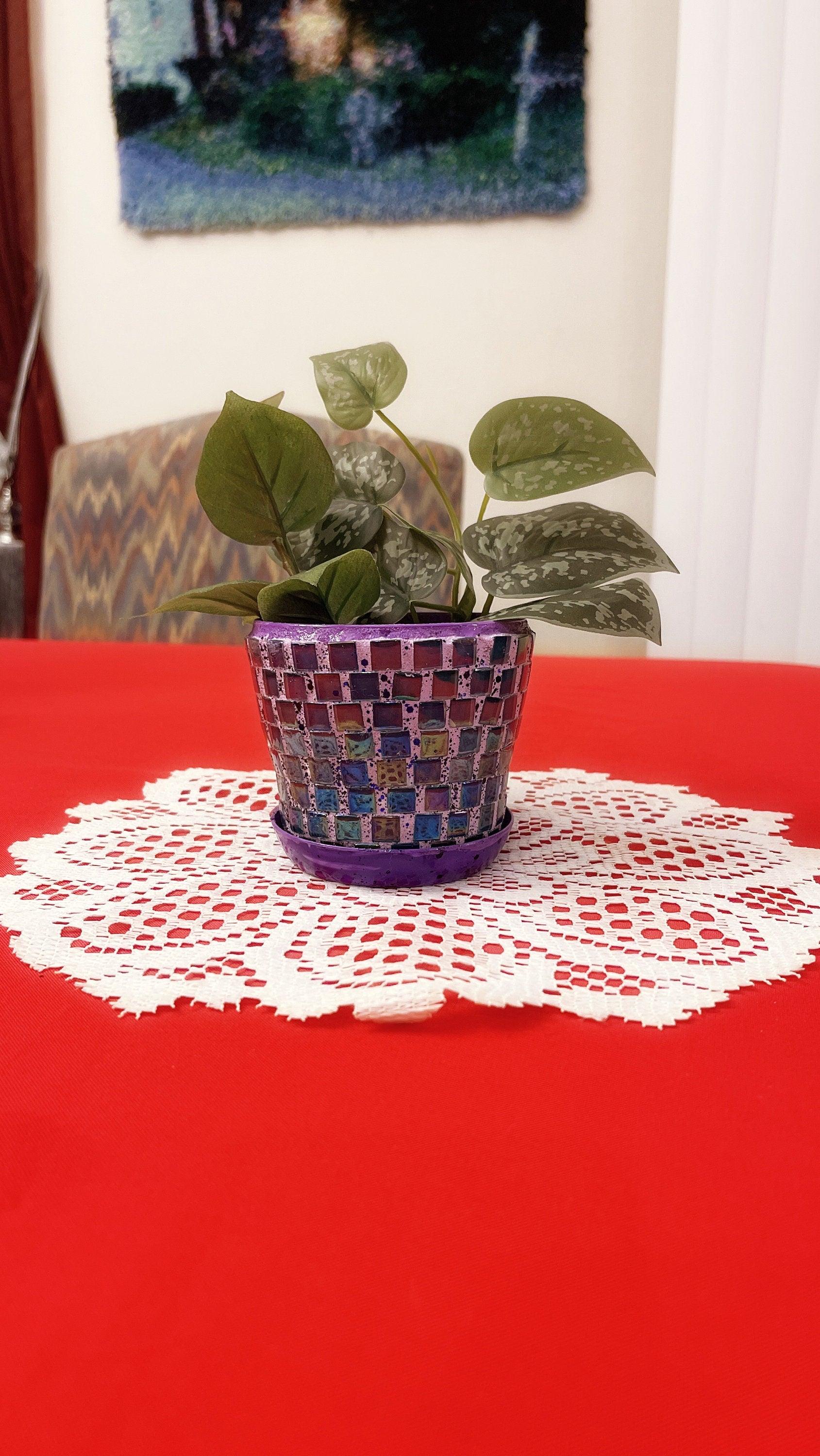 Purple and green mosaic flower pot with floral design, showcasing vibrant colors and intricate tile pattern.