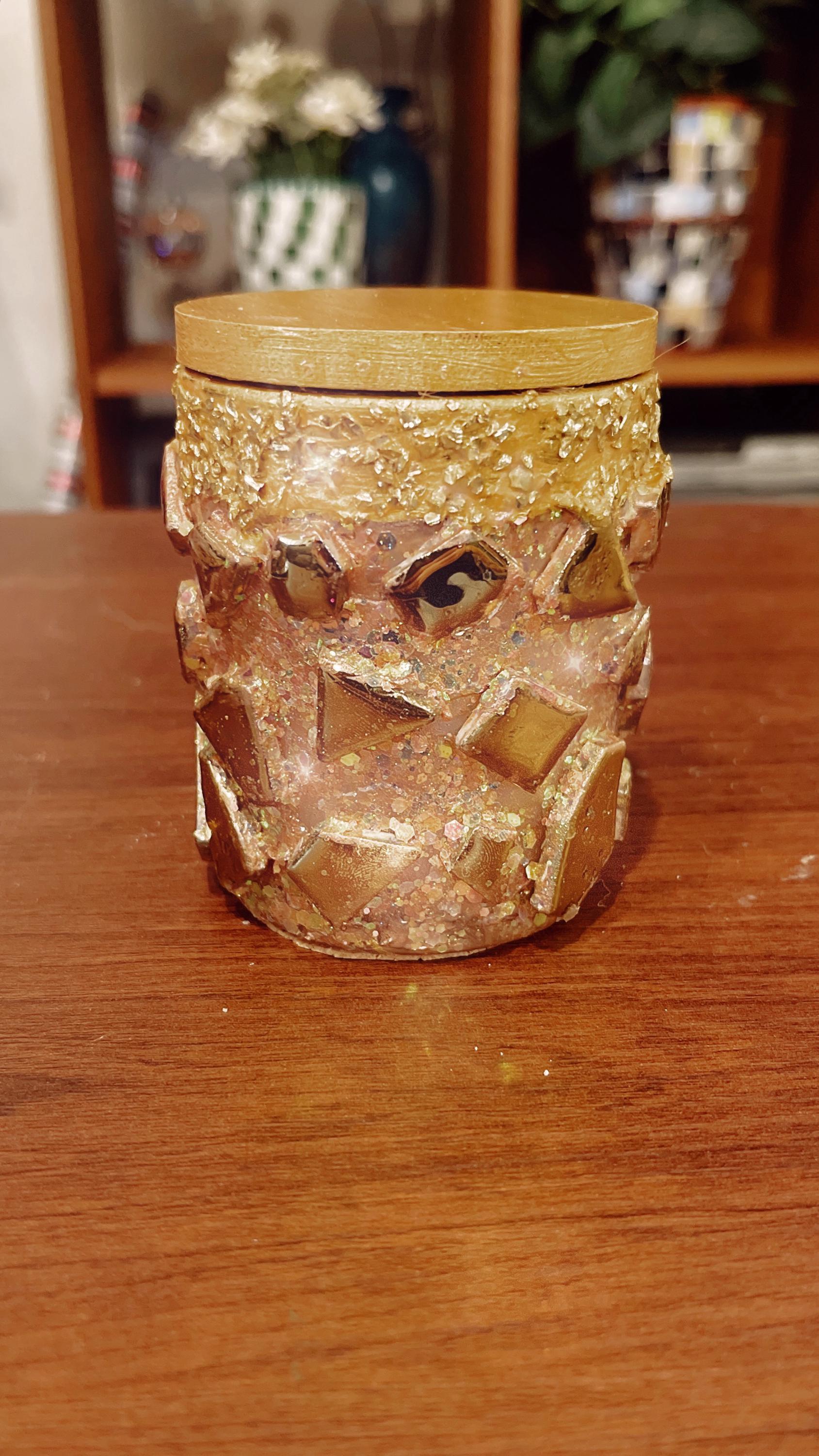 Handmade eucalyptus scented candle in a gold mosaic glass jar, showcasing intricate craftsmanship and warm candlelight.