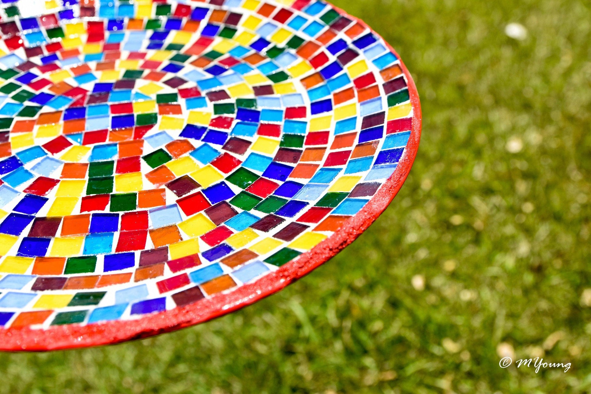 Colorful rainbow mosaic decorative wall plate with vibrant glass tiles, mounted on a neutral wall for artistic home decor.