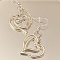 Triple layer heart dangle earrings with gold finish, featuring layered heart shapes hanging from delicate hooks.