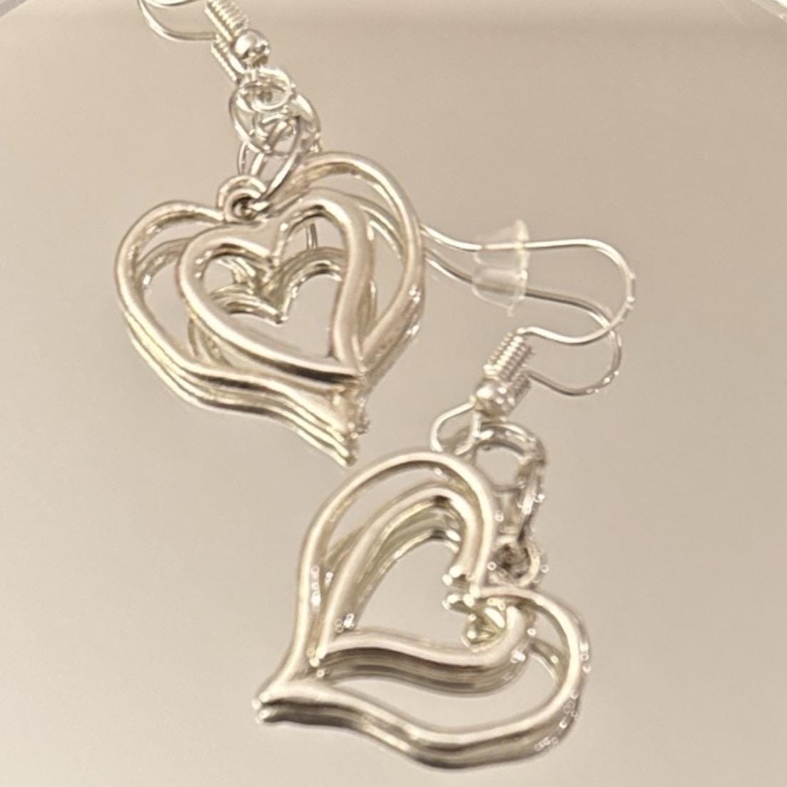 Triple layer heart dangle earrings with gold finish, featuring layered heart shapes hanging from delicate hooks.